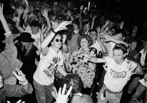 Historic black-and-white rave crowd with raised hands and dancers packed on the floor