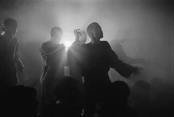 Historic black-and-white photo of silhouettes dancing in fog and backlight
